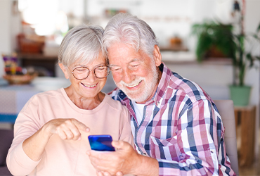 Elderly couple smiling sitting at home on video call