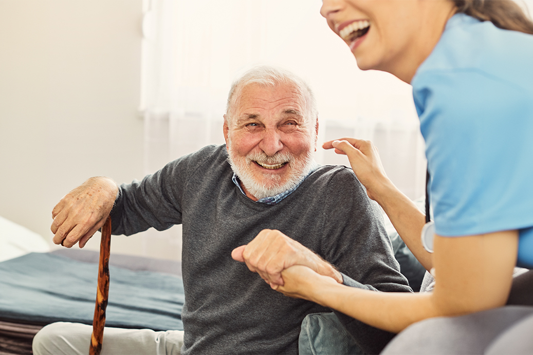 A nurse and an elderly gentleman enjoy a laugh together