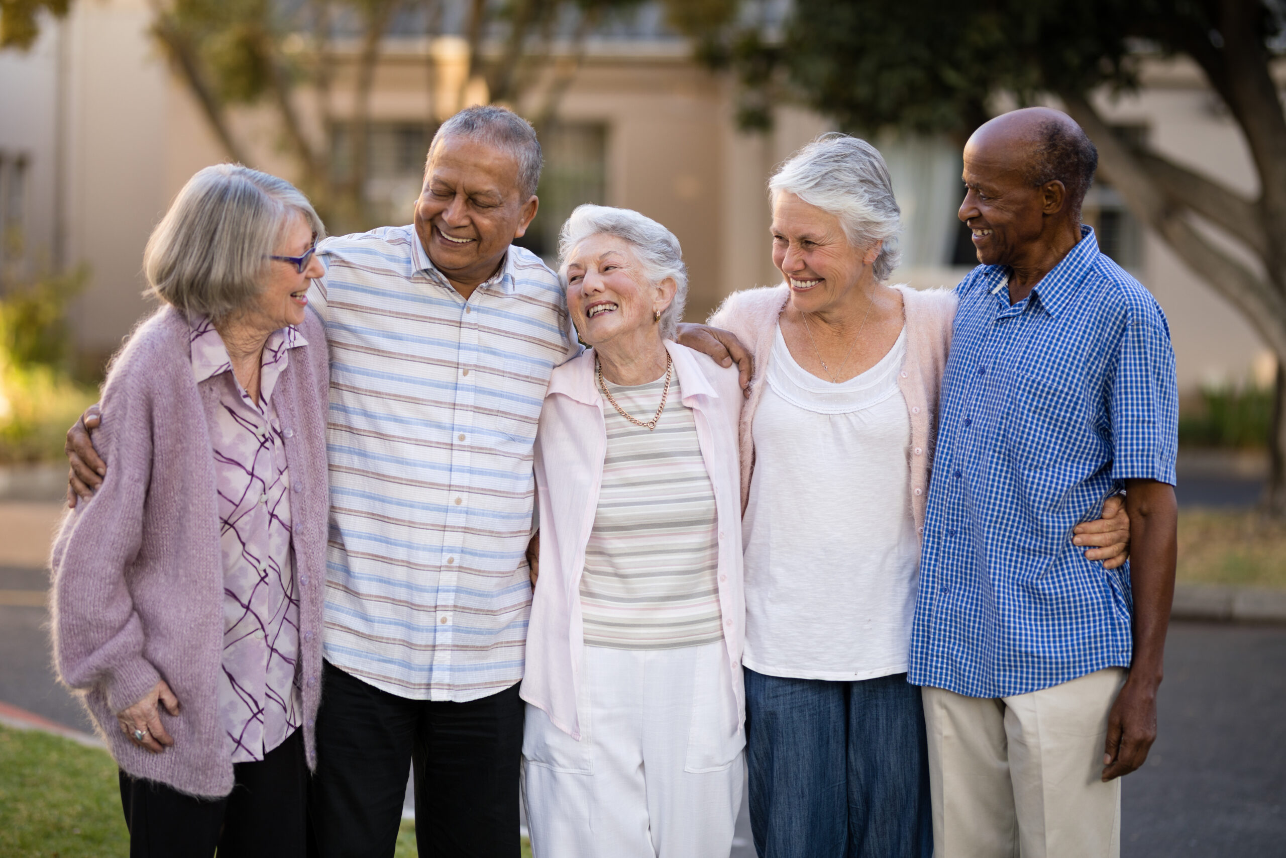 Smiling senior friends standing with arms around