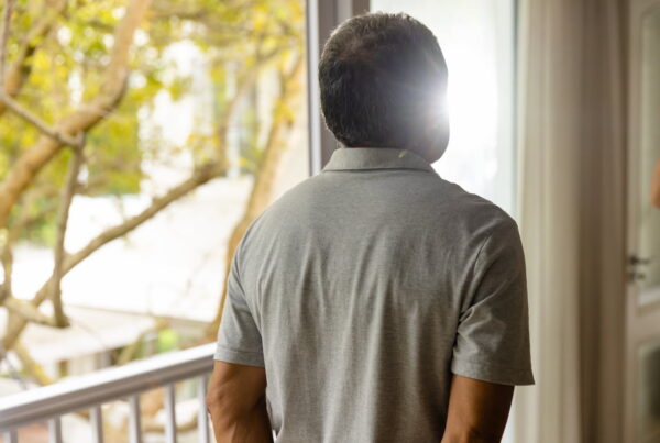 Back of senior resident man staying by window