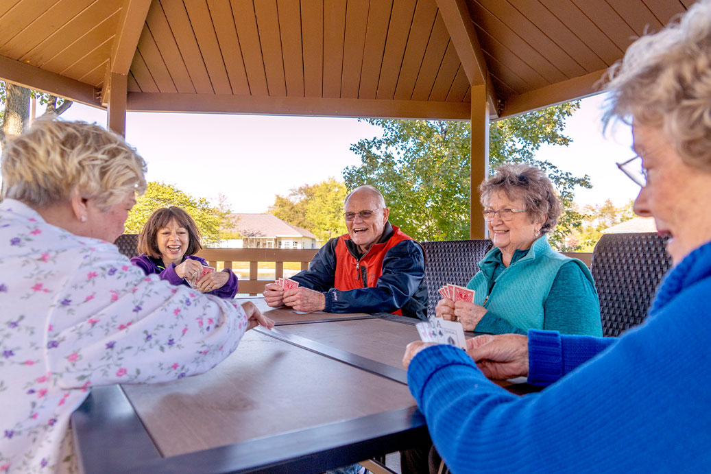 Westminster Village residents enjoying a card game outdoors as part of the benefits of Independent Living in Terre Haute